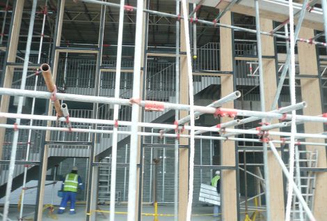 DITT workmen enter the entrance foyer after their lunchbreak. The wooden frames in the foreground will hold the glass that will feature a sculpture of living light. The builders are still waiting for the crane and the weather to install the heavy glass