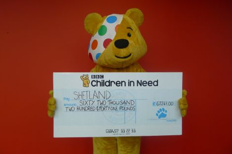 The Children in Need mascot Pudsey Bear handing over more than £62,000 to charities in Shetland - Photo: BBC