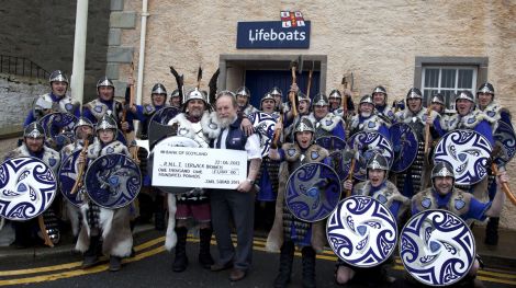 Lerwick lifeboat coxswain Bruce Leask accepting a cheque for £1,100 from guizer jarl Stvie Grant and his squad - Photo: RNLI