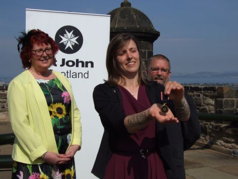 Proud parents Wynne and Derrick look on as Jessica shows off her medal at the Castle Esplanade in Edinburgh.