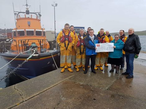 Members of the Lerwick Lifeboat crew accepting George and Wilma Miller's generous golden wedding gesture.