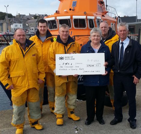 Lerwick lifeboat coxswain Alan Tarby (centre) accepts the donation from Alan and Sunniva Leask. Looking on are from left to right crew members Ian Harms, Grant Masson and John Best. Photo: RNLI