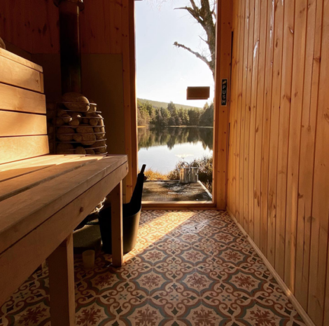 Sauna with an open door overlooking a serene lake.