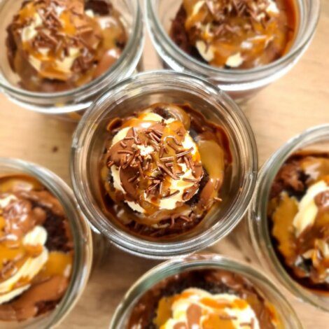 Jars of layered dessert with chocolate, caramel, and cream, viewed from above.