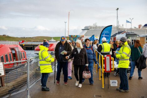 Passengers disembarking from a boat and walking through a security checkpoint at a harbor.