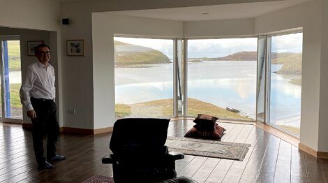 A man standing in a living room with a view of a lake.