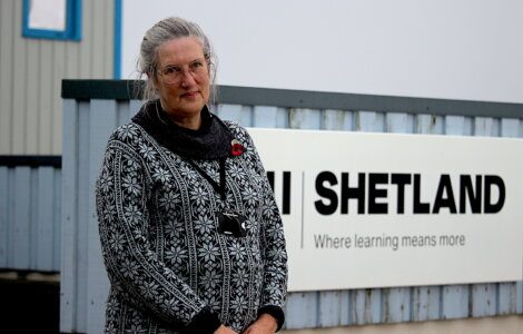 A woman standing in front of a shetland sign.