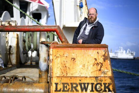 A man with a beard standing next to a boat.
