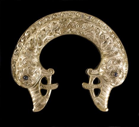A gold brooch with an ornate design on it.