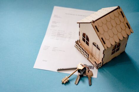 A house model on top of a paper and keys.