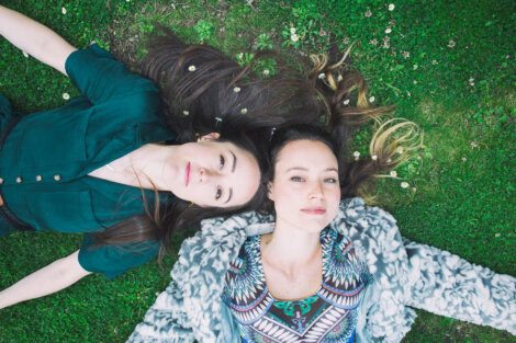 Two women laying on the grass with their hair down.