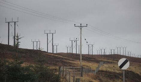 A group of power poles on a hillside.