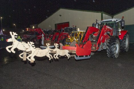 A tractor pulling a sleigh with reindeer on it.