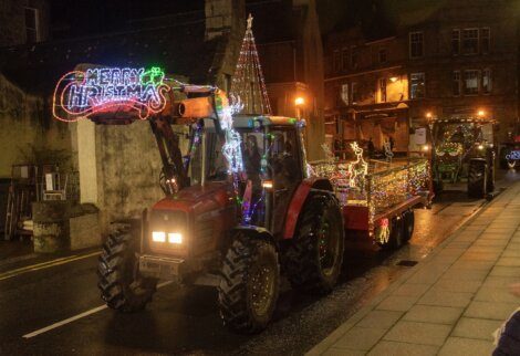 A tractor driving down a street with lights on it.