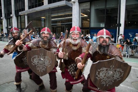 Three vikings dressed in armor walking down the street.