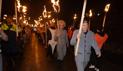 A group of people with torches walking down a street.