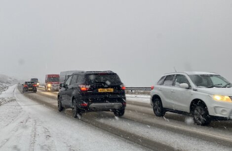 A group of cars driving on a snowy road.