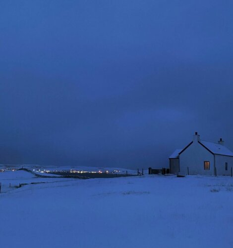 A house in a snow covered field at night.