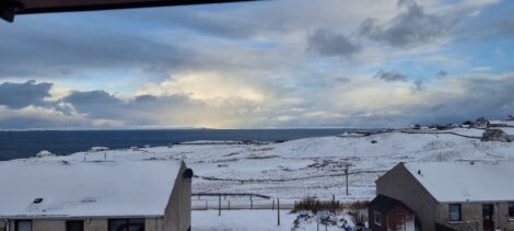 A view of snow covered houses and the ocean.