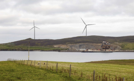Wind turbines on a hill next to a body of water.