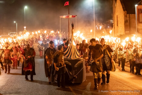 A group of people with torches walking down a street.