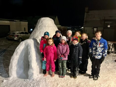 A group of people posing in front of an igloo.
