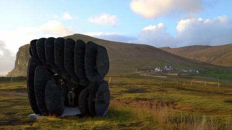 A black sculpture in the middle of a grassy field.