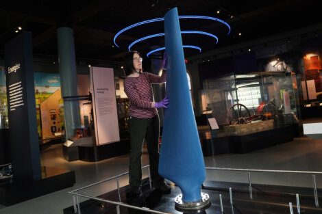 A woman standing next to a blue object in a museum.