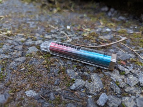 A blue and red cigarette laying on the ground.