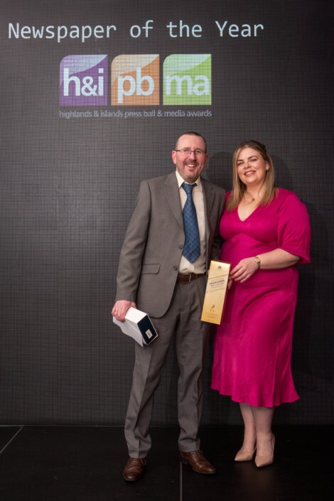 A man and woman posing with an award for newspaper of the year.
