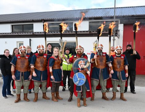 Group of people dressed in viking costumes with flaming torches posing for a photo.