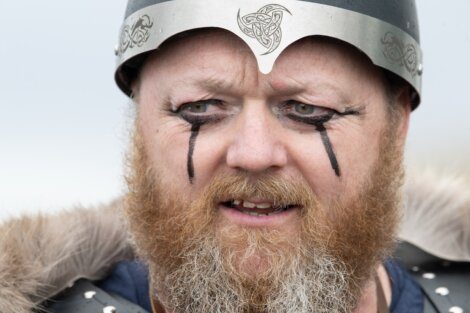 A man in viking costume with face paint and a helmet.