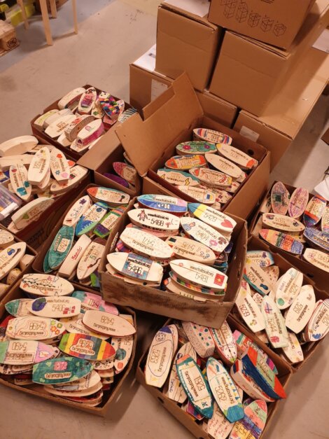 Boxes filled with numerous hand-painted, colorful ceramic plates in various designs, stacked for display in a shop.